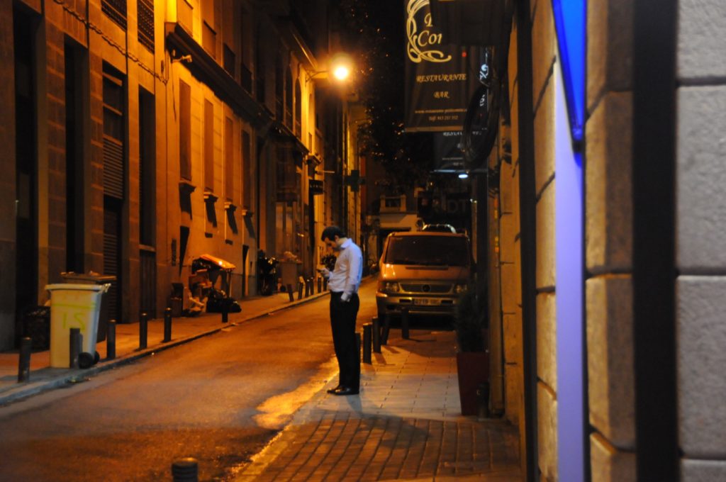 Man checking cell phone on a street in Madrid.