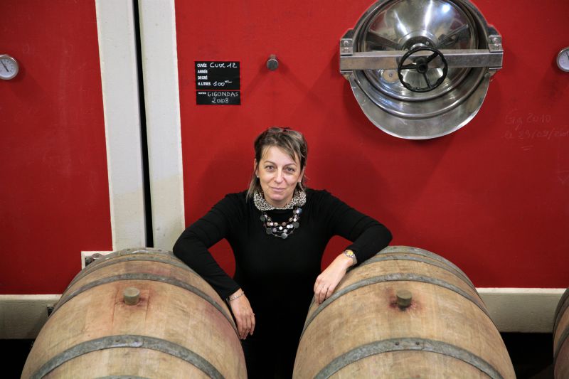 Véronique Cunty of Domaine de Font-Sane standing between two wine barrels.