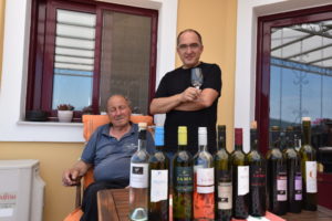 Konstantinos Vriniotis and his father standing with the line up of wines from Vriniotis winery