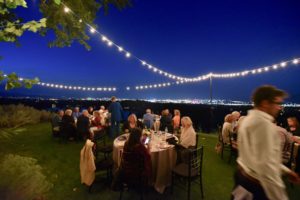 Dining under the stars with string of lights around with the city lights in the distance.