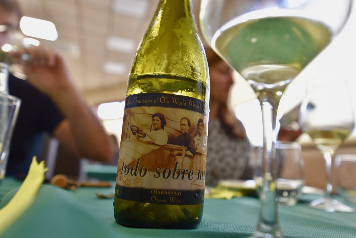 Bottle of Chardonnay on a table next to a glass of wine.