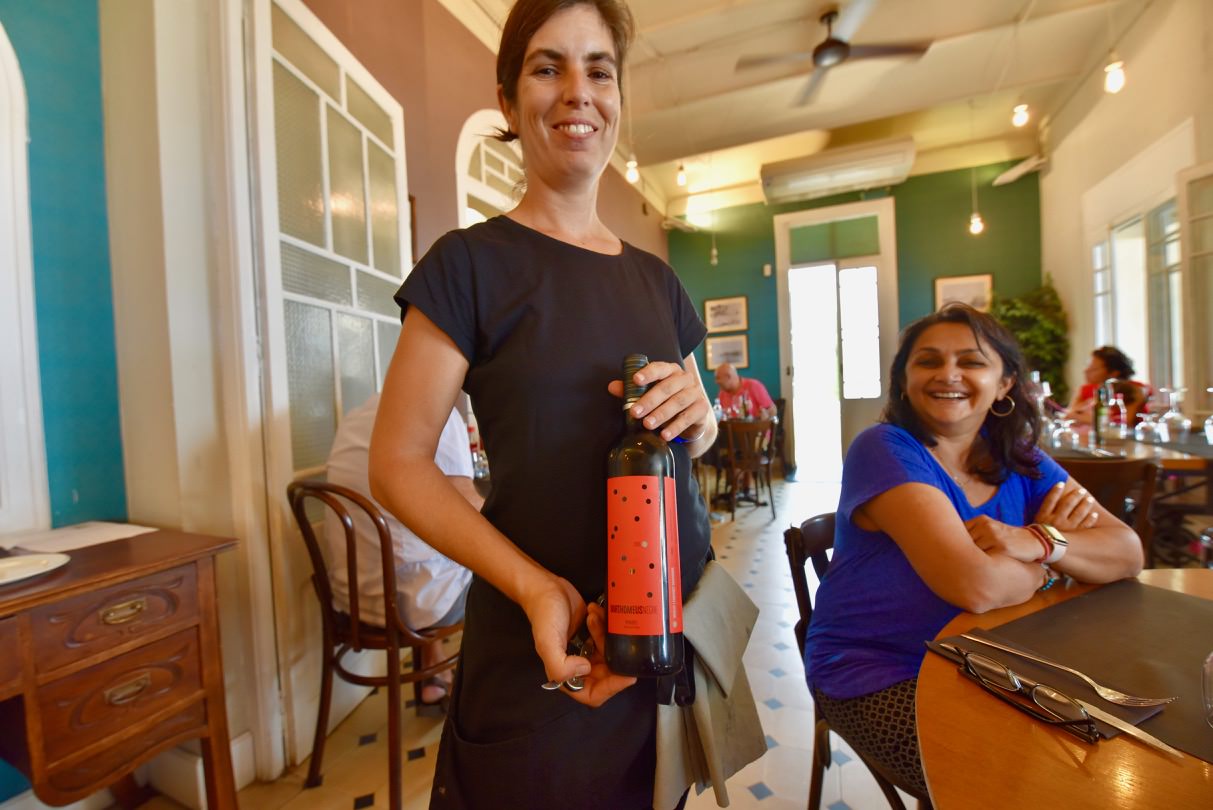 Woman holding the bottle of red wine from the Barthomeus winery and another woman smiling at her.