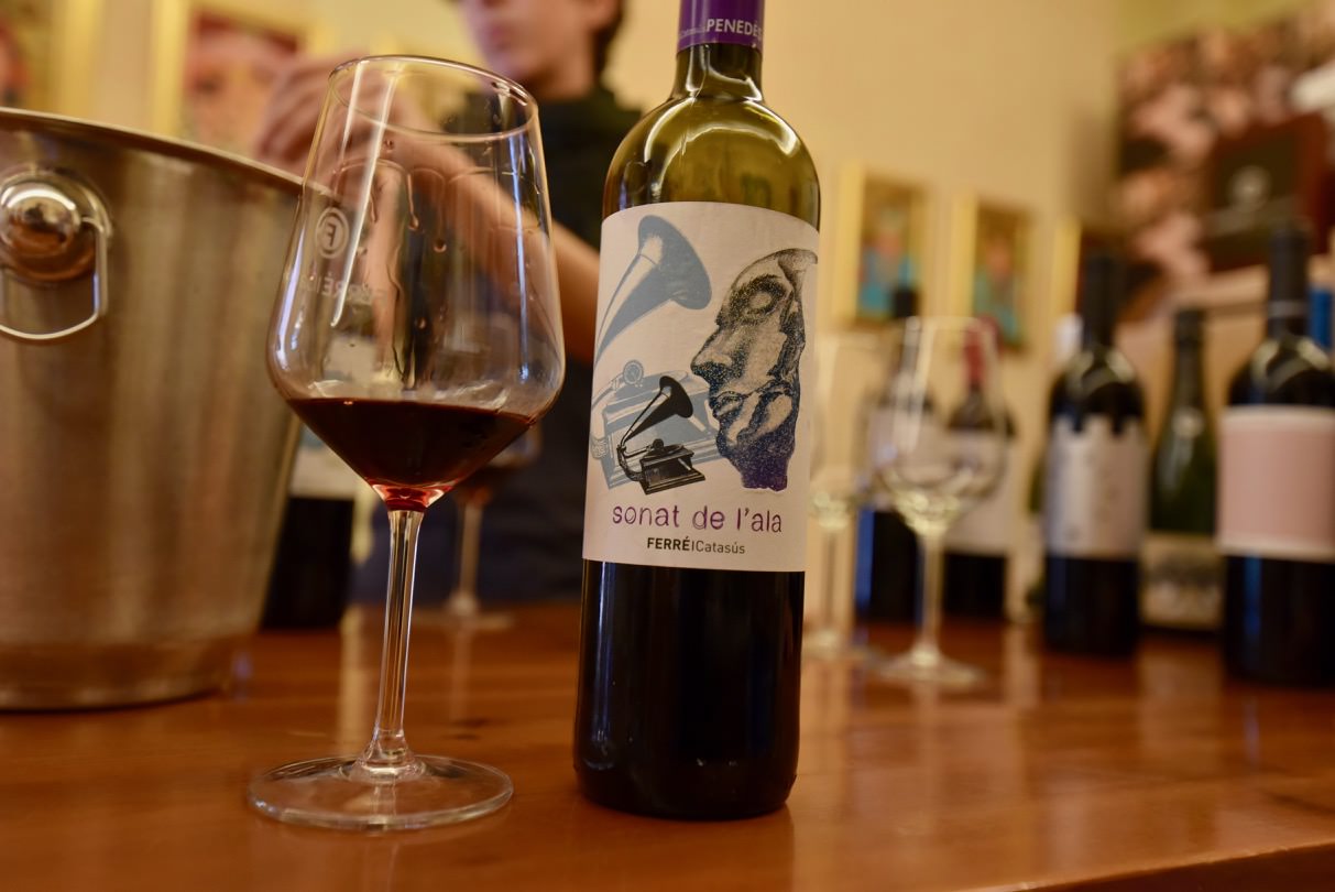 Bottles of wine on a table with a glass of red wine.