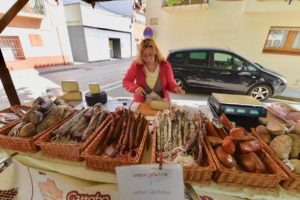 A lady selling sausages and meat at a farmers market in Spain.