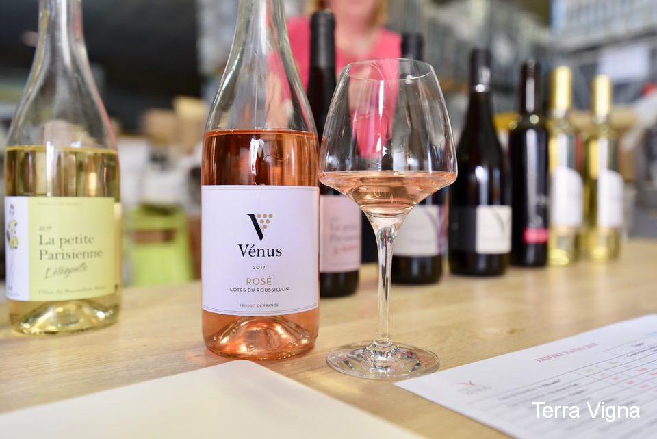 Bottles of wine on a table and a bottle of rosé wine in front with some wine in a glass.