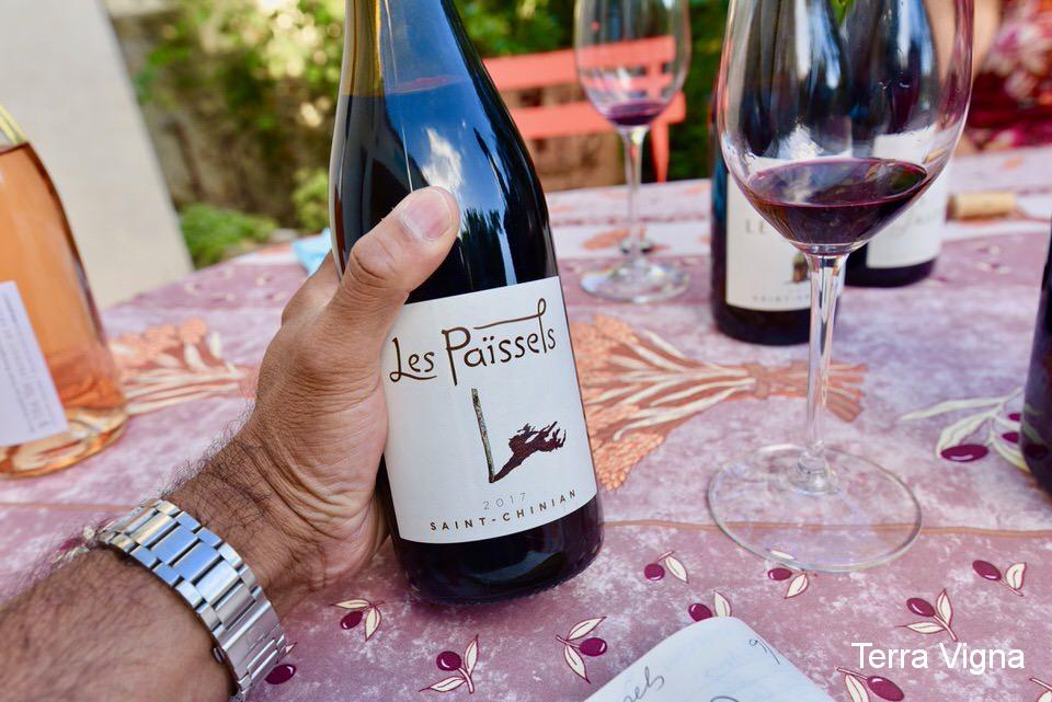 A hand holding a bottle of wine from Les Paissels in Saint-Chinian