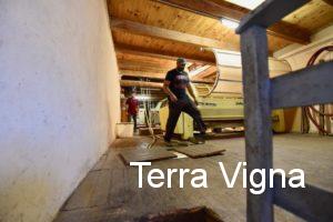 A man walking on the wooden floor in the garage winery of Les Paissels.