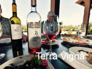 Two bottles of wine on a table next to a glass of Aidarini rose of Xinomavro.