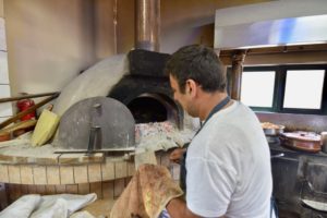 A man checking a brick oven.