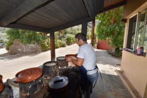 A man cooking on some clay pots.