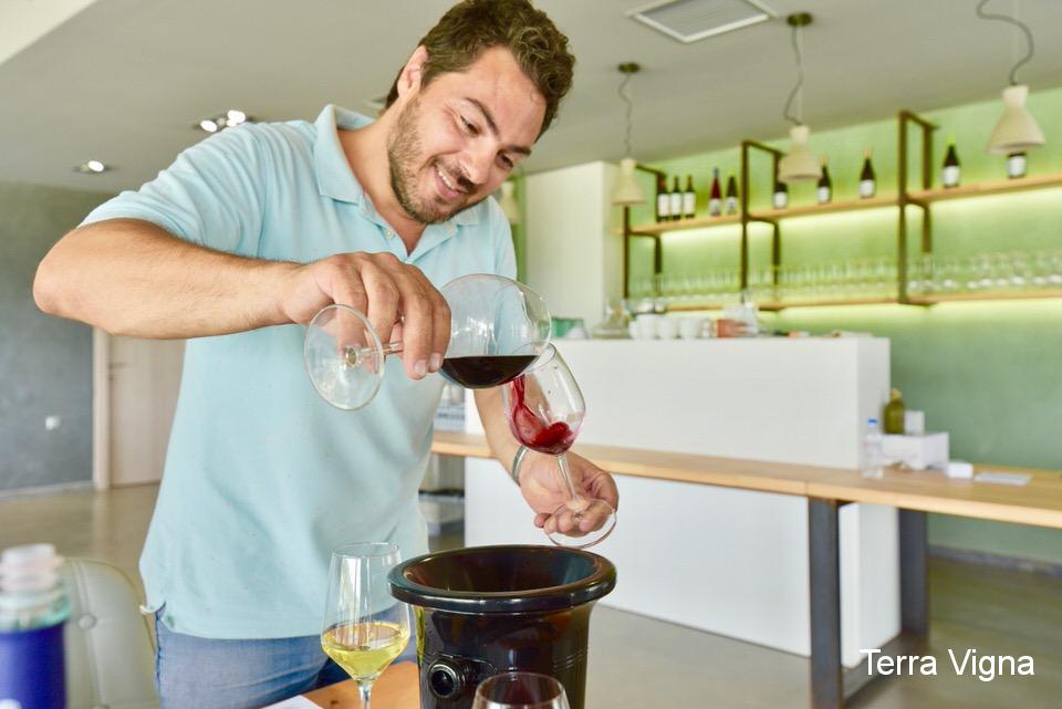 A man smiling and pouring red wine form one glass to another.
