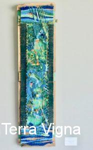 A loom made weave art work hanging on a wall.