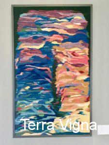 A loom made weave art work hanging on a wall.