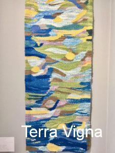 A loom made weave art work hanging on a wall.